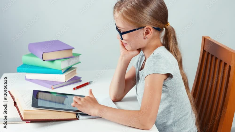 Portrait profile student girl child 7-8 years old using tablet pc in her desk and looking at camera with smile. Top view Portrait profile student girl child 7-8 years old using tablet pc in her desk and looking at camera with smile. Top view