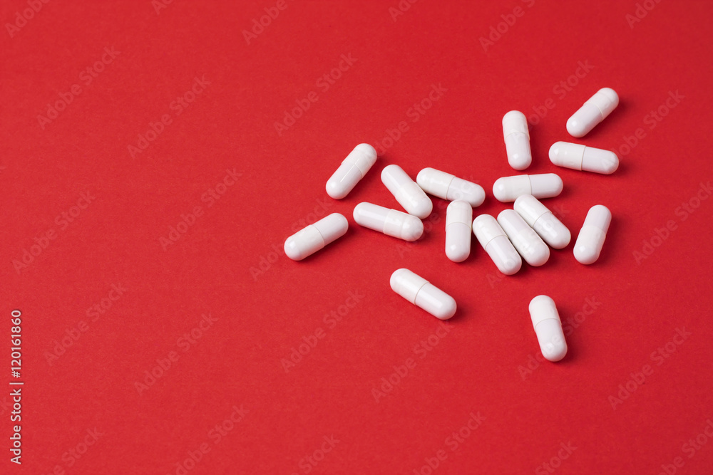 White capsules on red background White capsules on red background