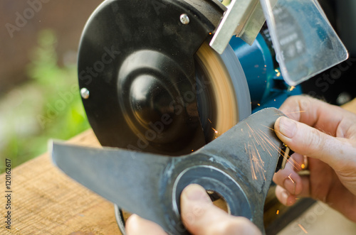 Worker sharpening his blade lawn mower.