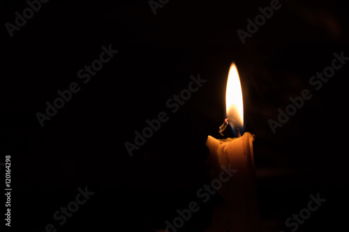 One light candle burning brightly, image is isolated against a b