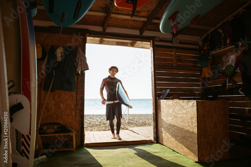 Sports man going to the beach shack with surf board