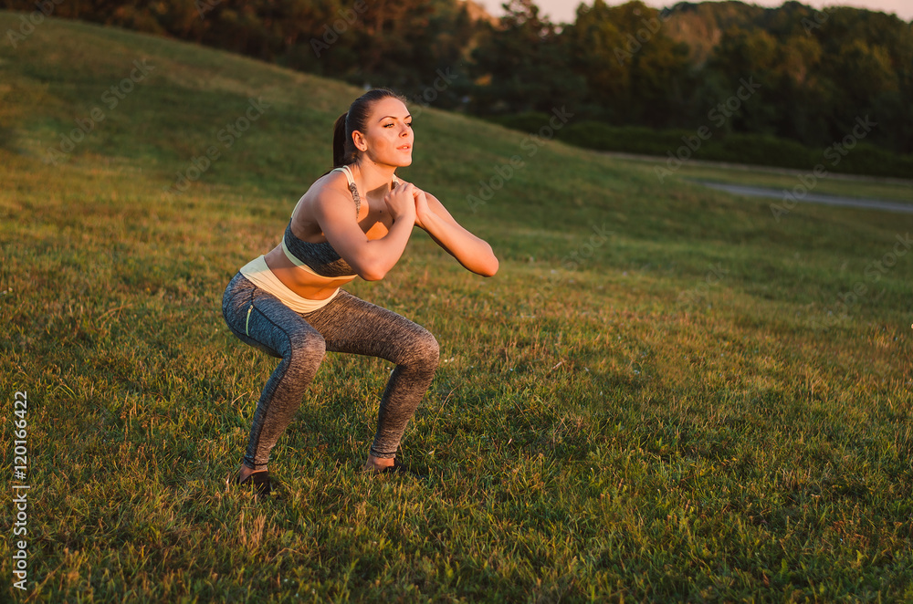 Attractive fitness woman practicing in the park on the grass. Sh Attractive fitness woman practicing in the park on the grass. Sh