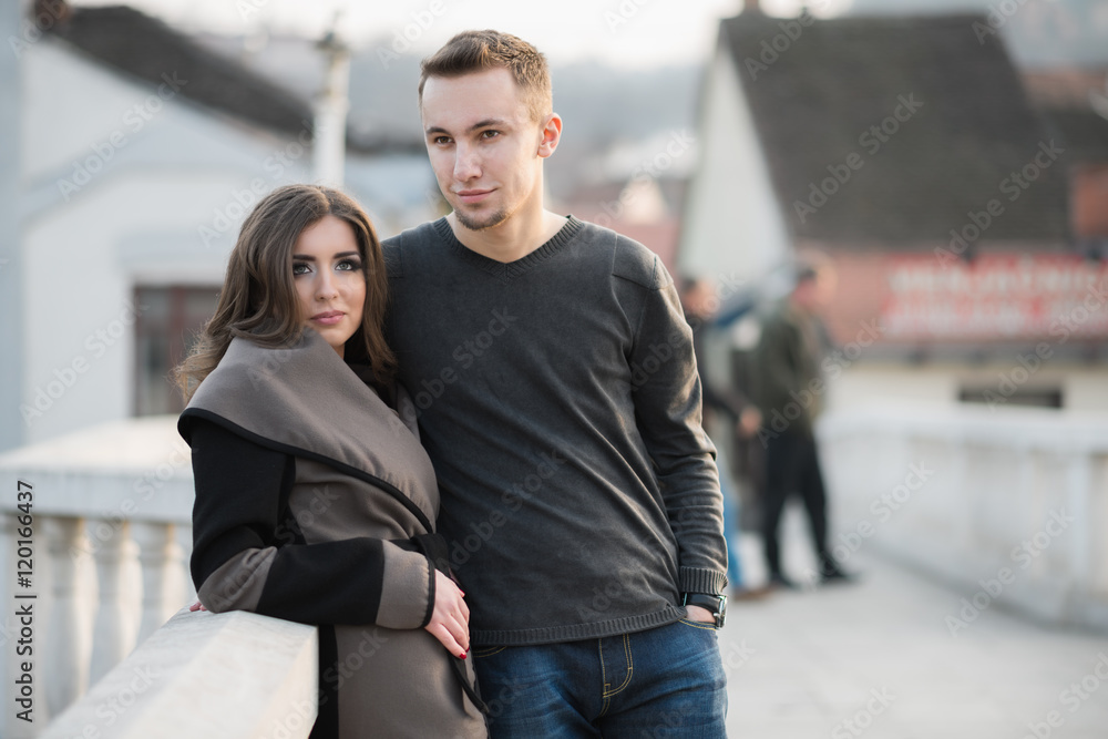 Beautiful young adult couple posing and looking at camera. They enjoy autumn outdoors. Warm sunlight. Beautiful young adult couple posing and looking at camera. They enjoy autumn outdoors. Warm sunlight.