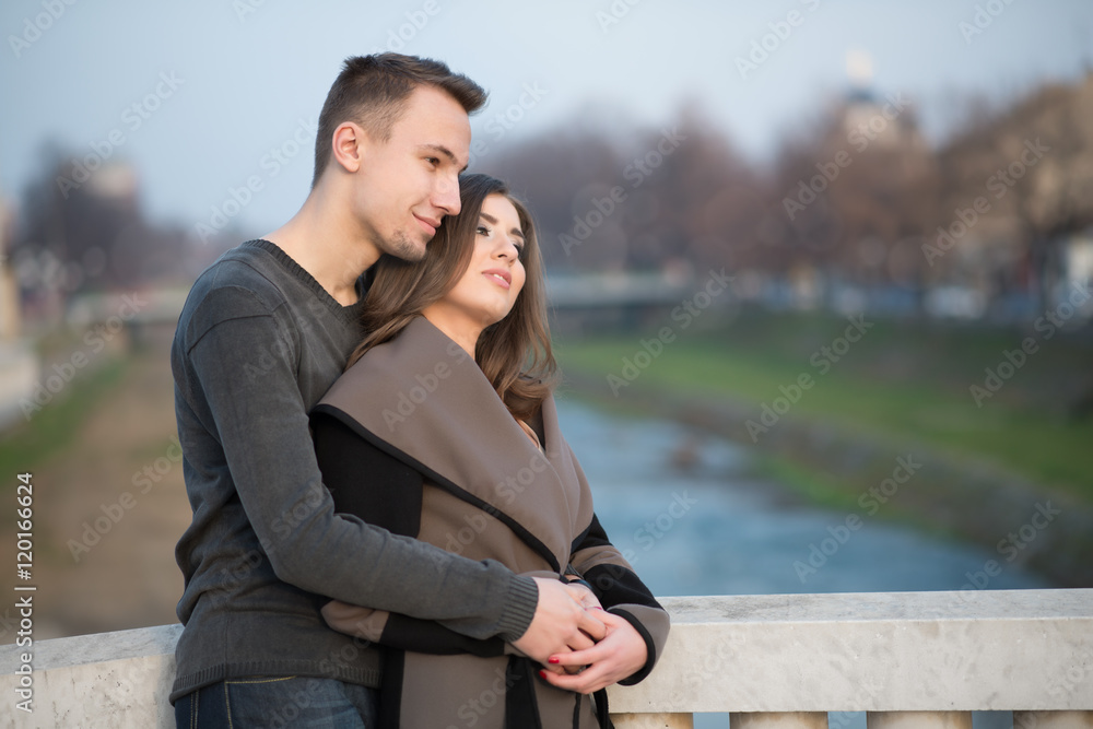 Beautiful young adult couple hugging and kissing. They enjoy autumn outdoors. Warm sunlight.