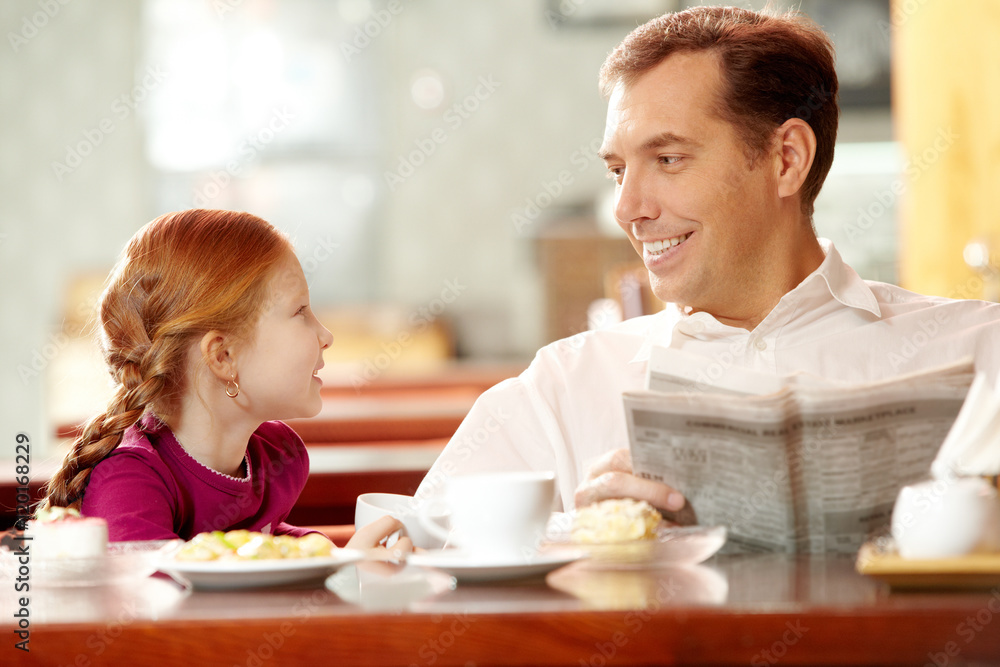 Little daughter sitting in cafe with her father