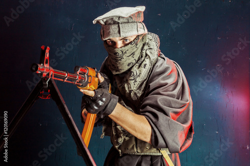 Man with rifle standing against colored background