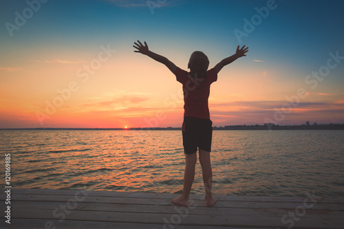 Little boy stays on a pier