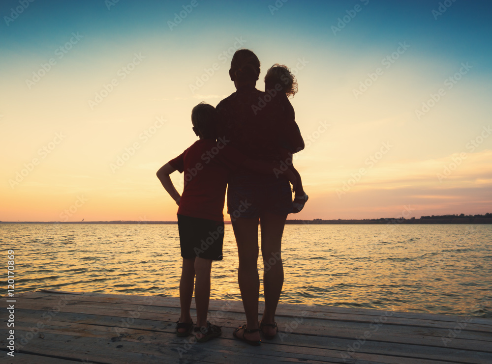 Silhouette of family watching sea sunset