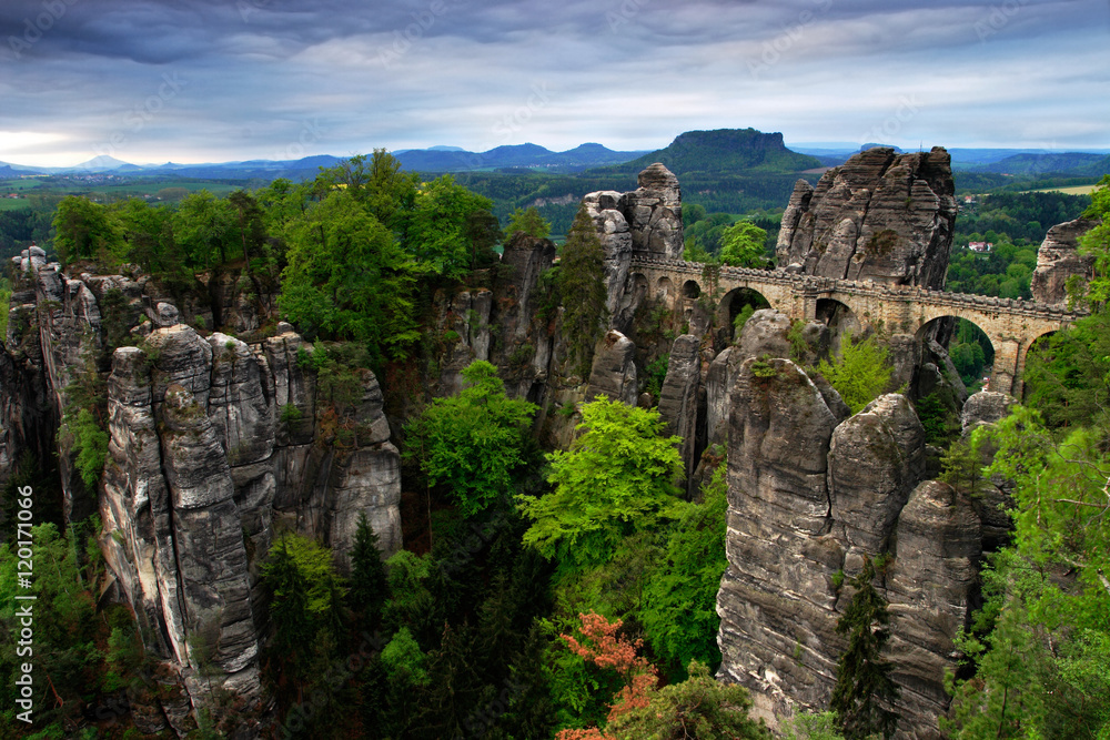 Bastei bridge in Saxon Switzerland, at sunrise and the mist over the river Elbe, National park Saxon Switzerland. Beautiful Germany landscape. Summer morning with grey clouds in the Bastei monument. 
