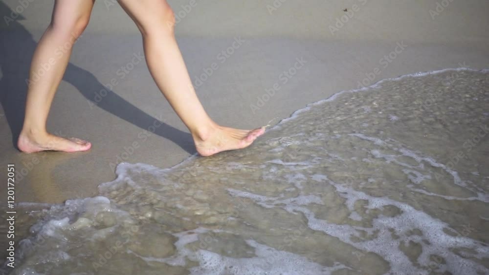 Knee-Deep View of a Girl's Legs Walking Along the Edge of the Sea. Slow Motion Knee-Deep View of a Girl's Legs Walking Along the Edge of the Sea. Slow Motion