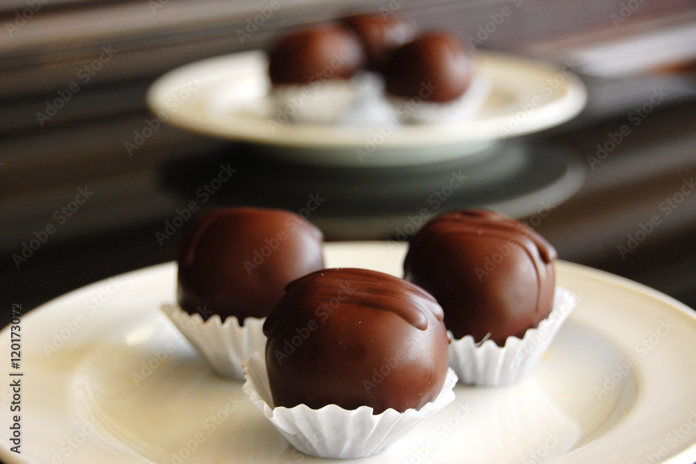 Assorted dark chocolate truffles with cocoa powder, coconut and chopped hazelnuts on a dessert plate Assorted dark chocolate truffles with cocoa powder, coconut and chopped hazelnuts on a dessert plate