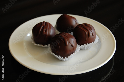 Assorted dark chocolate truffles with cocoa powder, coconut and chopped hazelnuts on a dessert plate