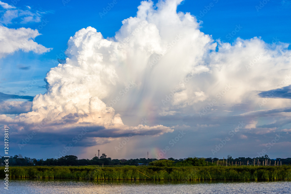 Afternoon cloudy sky with cumulonimbus with a small rainbow Afternoon cloudy sky with cumulonimbus with a small rainbow