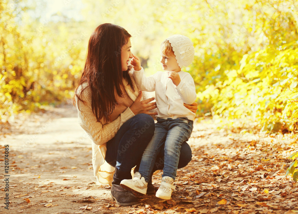 Happy smiling mother playing with child in warm autumn day