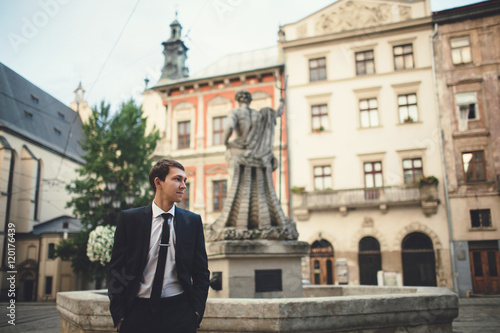 elegant man standing near the stone statues