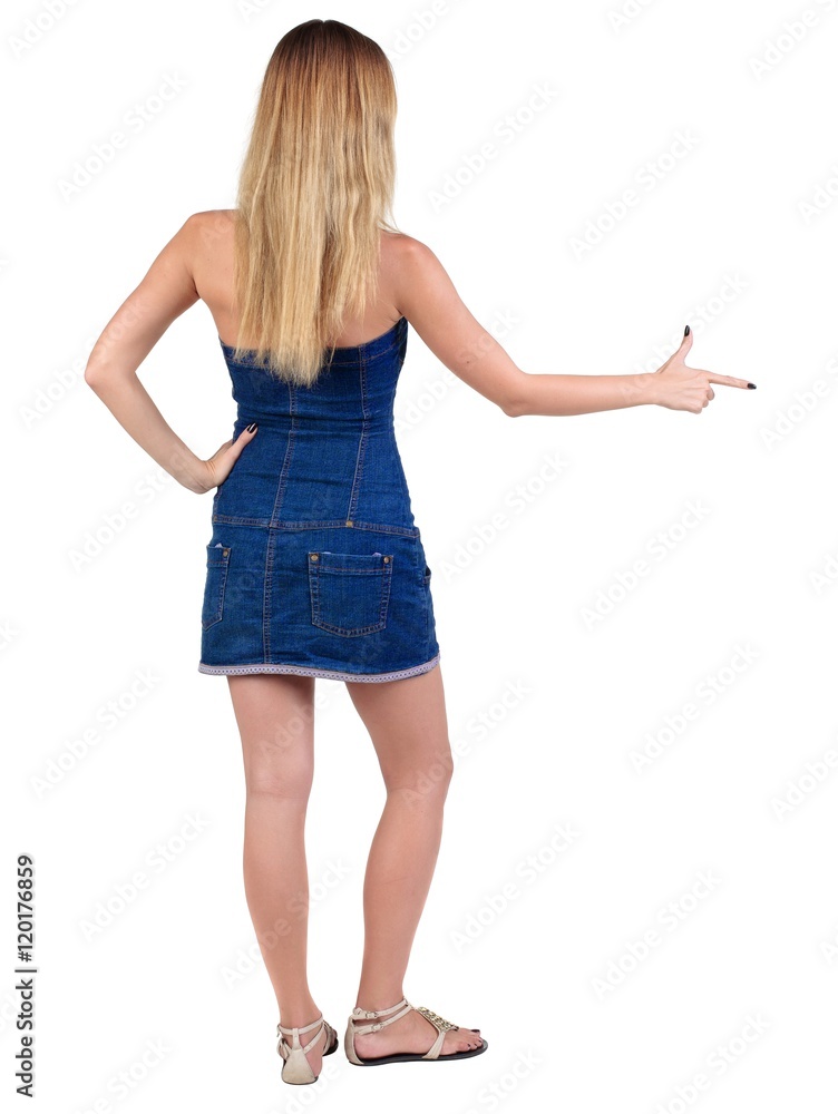 back of view beautiful young woman in jeans dress pointing at wall. rear view. Isolated over white . back of view beautiful young woman in jeans dress pointing at wall. rear view. Isolated over white .