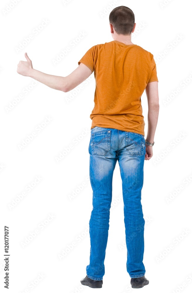 Back view of young men in orange t-shirt going thumb up. Rear view. Isolated over white background. Guy looks away and showing of positive emotions with OK sign concept . Back view of young men in orange t-shirt going thumb up. Rear view. Isolated over white background. Guy looks away and showing of positive emotions with OK sign concept .