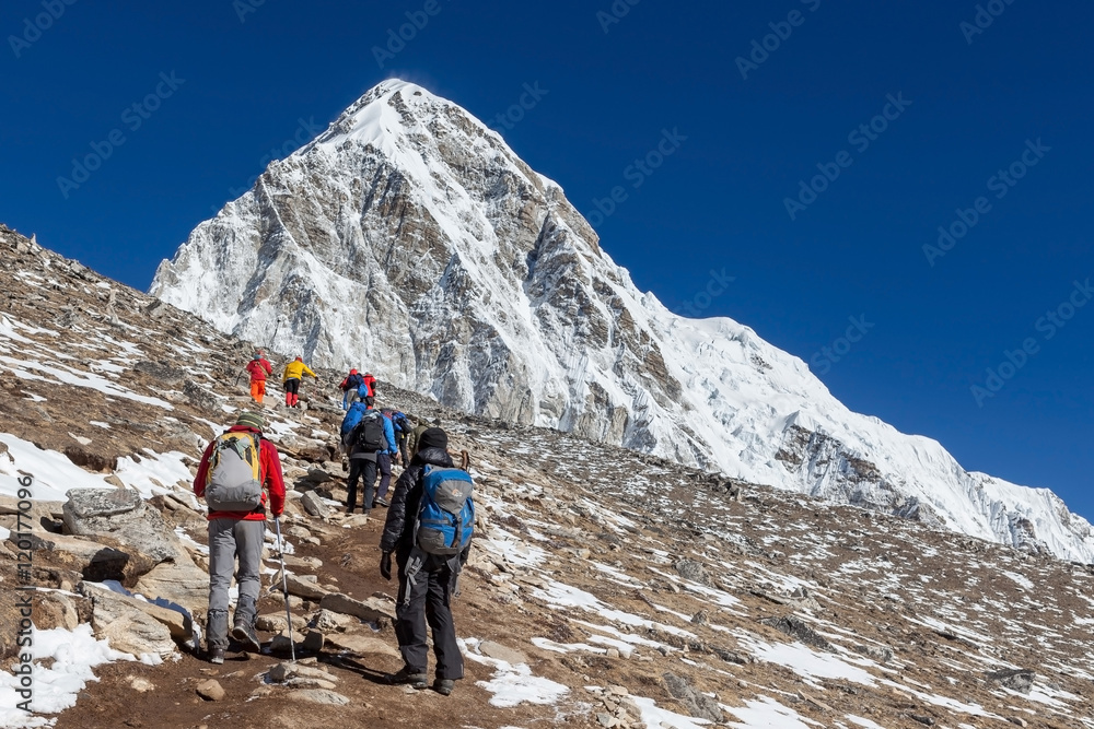 Group of trekkers coming up to Kala Patthar - the Everest mount view point - with Pumori peak on the background. Trail leading up to the Kala Pattar hill near Everest Base Camp, Himalayas, Nepal.