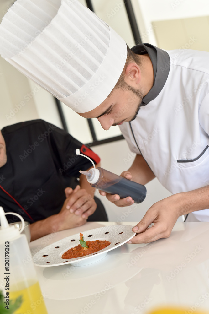 Cook student preparing dish with help of chef Cook student preparing dish with help of chef