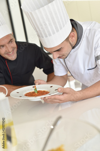 Cook student preparing dish with help of chef