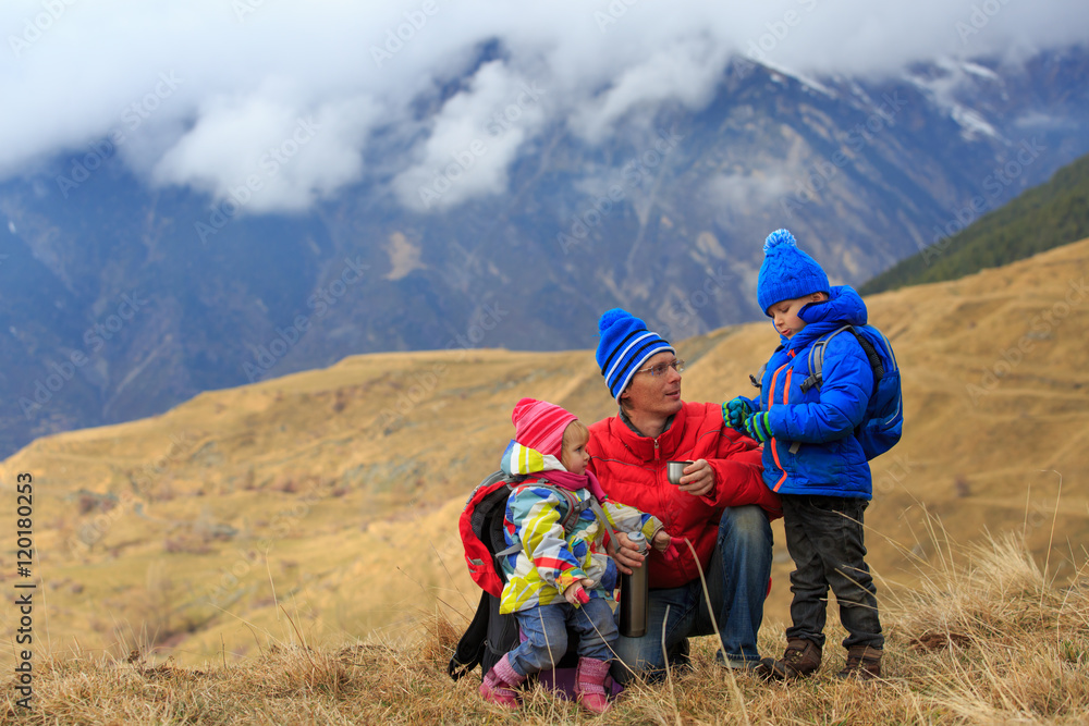 father with two kids hiking in winter mountains