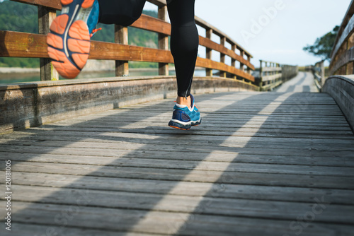 man running in park on wooden walkway training and exercising for trail run marathon race. Fitness healthy lifestyle concept with male athlete outdoor runner.