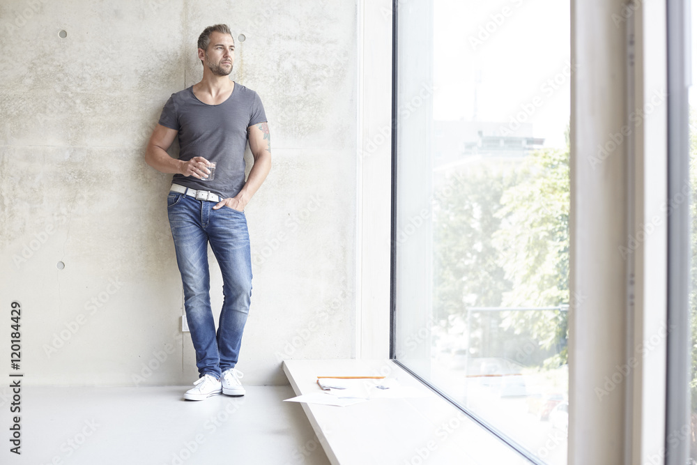 Man holding glass of water looking out of window Man holding glass of water looking out of window