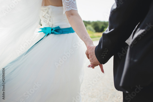 Groom is holding a hand of his bride