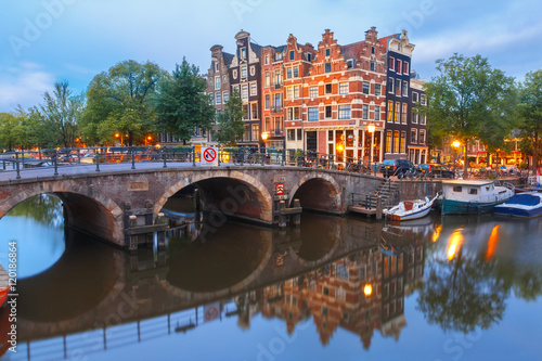 Amsterdam canal, bridge and typical houses, boats and bicycles during morning twilight blue hour, Holland, Netherlands.