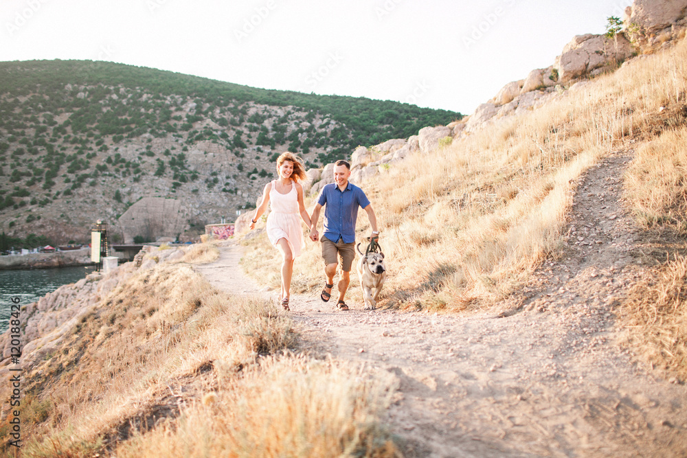 Couple of guys playing with their dog on the mountain near ocean. Romantic time in nature with beautiful view. Couple of guys playing with their dog on the mountain near ocean. Romantic time in nature with beautiful view.