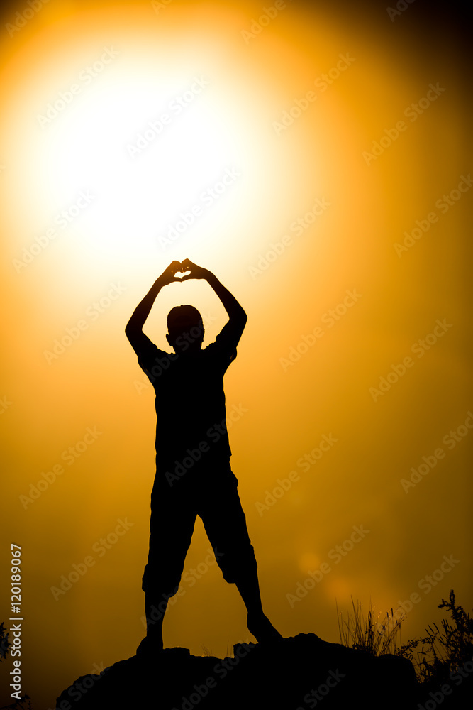 Silhouetted friend forming a heart symbol at golden hour sunset Silhouetted friend forming a heart symbol at golden hour sunset