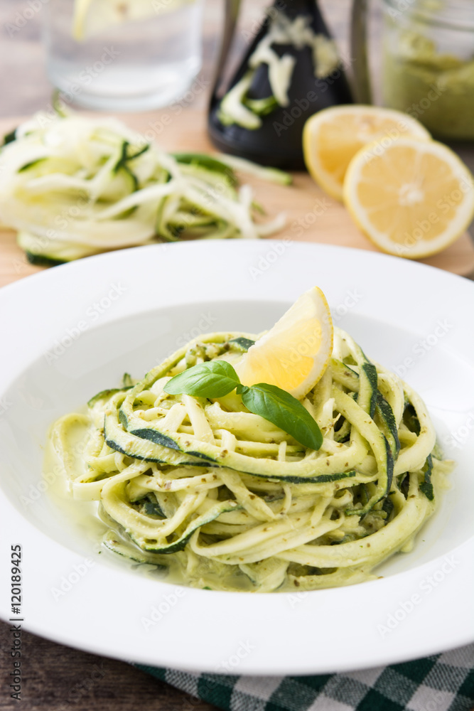 Zucchini noodles with pesto sauce on wooden table

