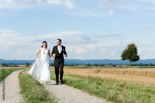 Brautpaar läuft auf einem Feldweg