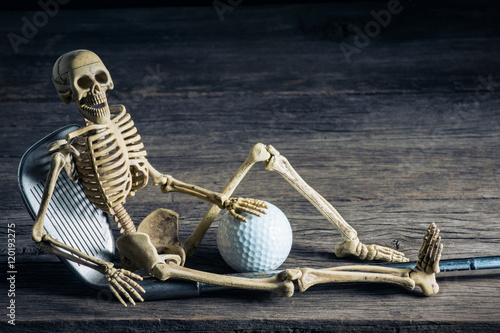 skeleton sitting with golf equipment on old wood