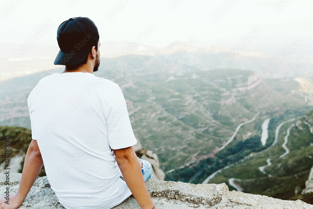 Naklejka premium Handsome young man enjoying nature at mountain peak.