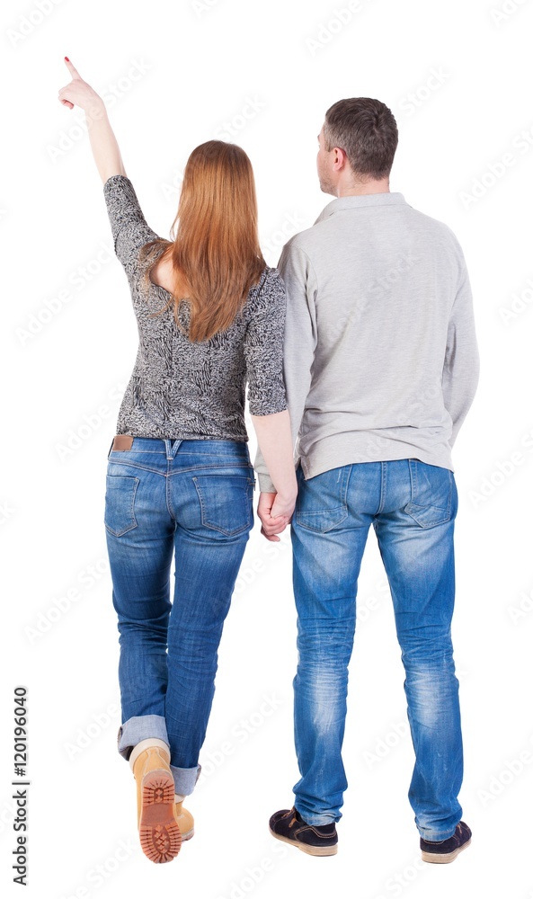 young couple pointing at wal Back view (woman and man). Rear view ...