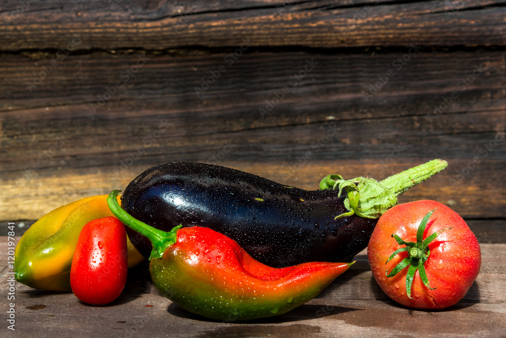 colored bell peppers, eggplant, tomatoes on wooden background