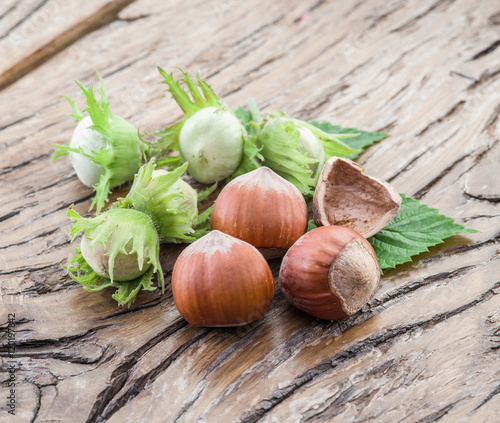 Young hazelnuts and ripe brown hazelnuts on the wooden table.