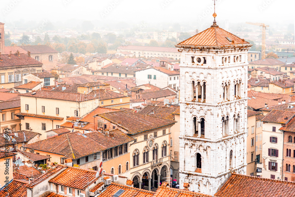 Aerial cityscape view on the old town of Lucca with San Michele basilicas tower at the foggy weather in Italy