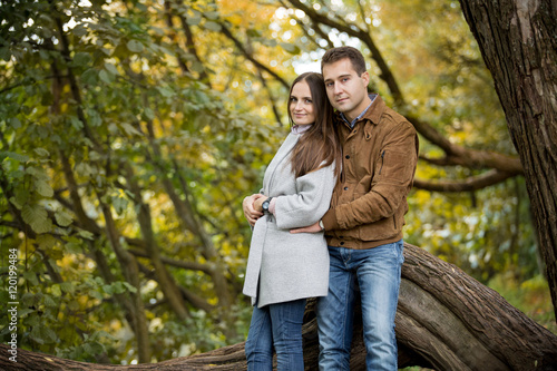 Romantic couple relaxing in autumn park, cuddling, kissing, enjoying fresh air, beautiful nature, nice fall weather. Beloved spending time together. Yellow leaves in background