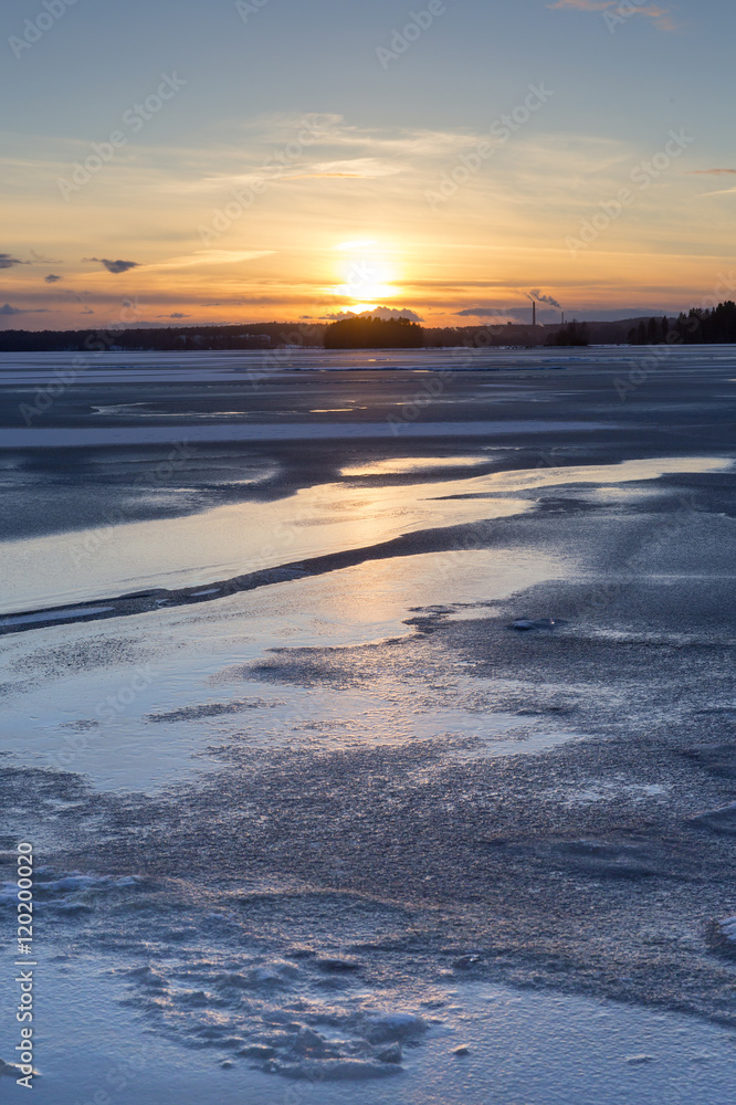 A beautiful sunset by the icy lake. The ice is reflecting the colors of the sunset. Image taken in Finland after a cold winter day. A beautiful sunset by the icy lake. The ice is reflecting the colors of the sunset. Image taken in Finland after a cold winter day.