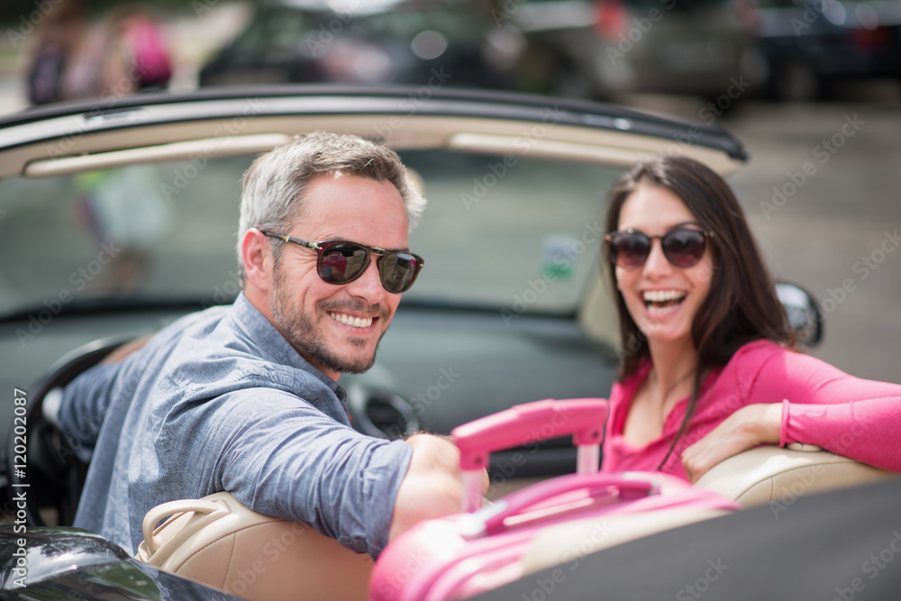 cheerful couple going on a road trip in their convertible car cheerful couple going on a road trip in their convertible car