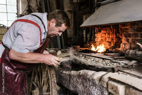 Blacksmith hardening chisel checking the glow color
