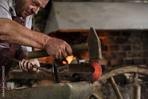 Blacksmith working on hook using hammer and thorn photo