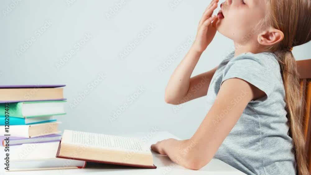 Close up portrait profile girl child 7-8 years old reading textbook and yawning. Isolated Close up portrait profile girl child 7-8 years old reading textbook and yawning. Isolated