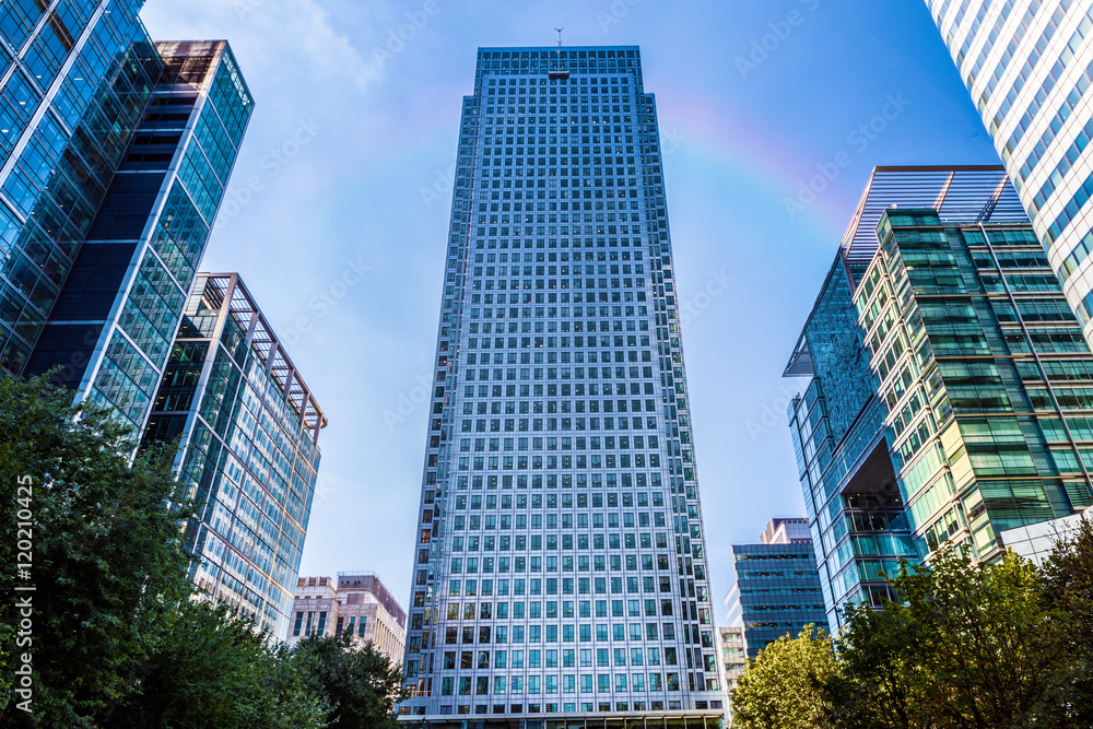 Office building in Canary Wharf, financial district of London with a faded rainbow in the background