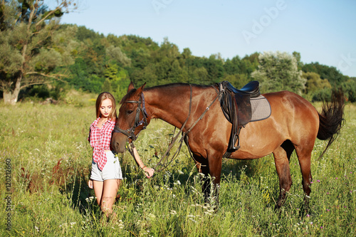 девушка блондинка с на прогулке с лошадью в поле