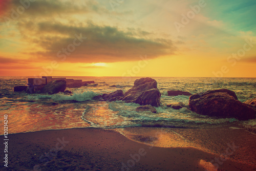 Sea coast after sunrise with rocks, blue water and sunny sky, natural seasonal summer hipster background
