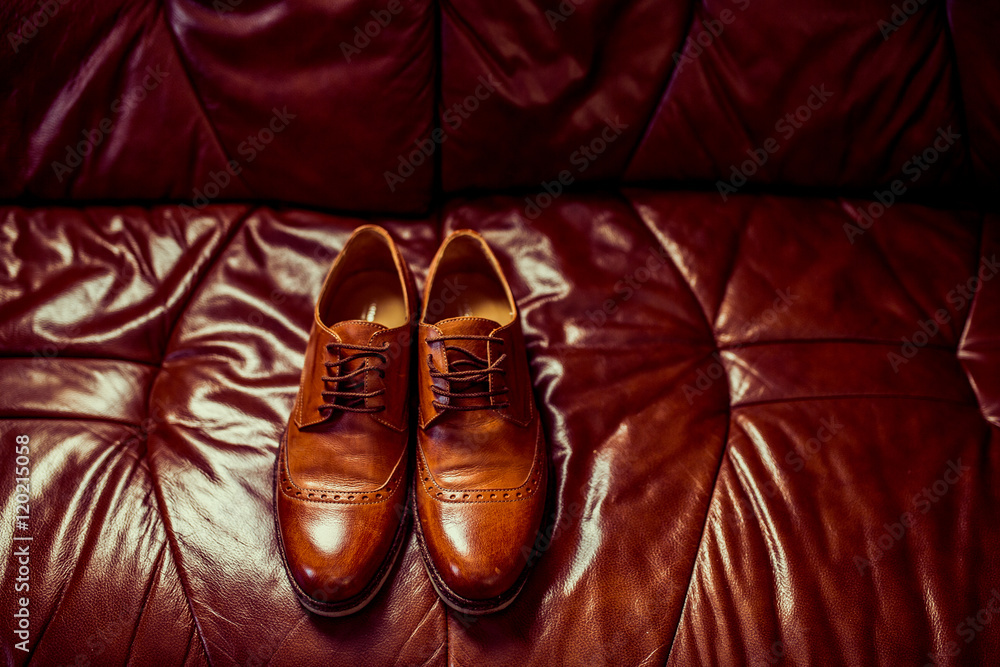 Male luxury brown leather shoes on sofa.