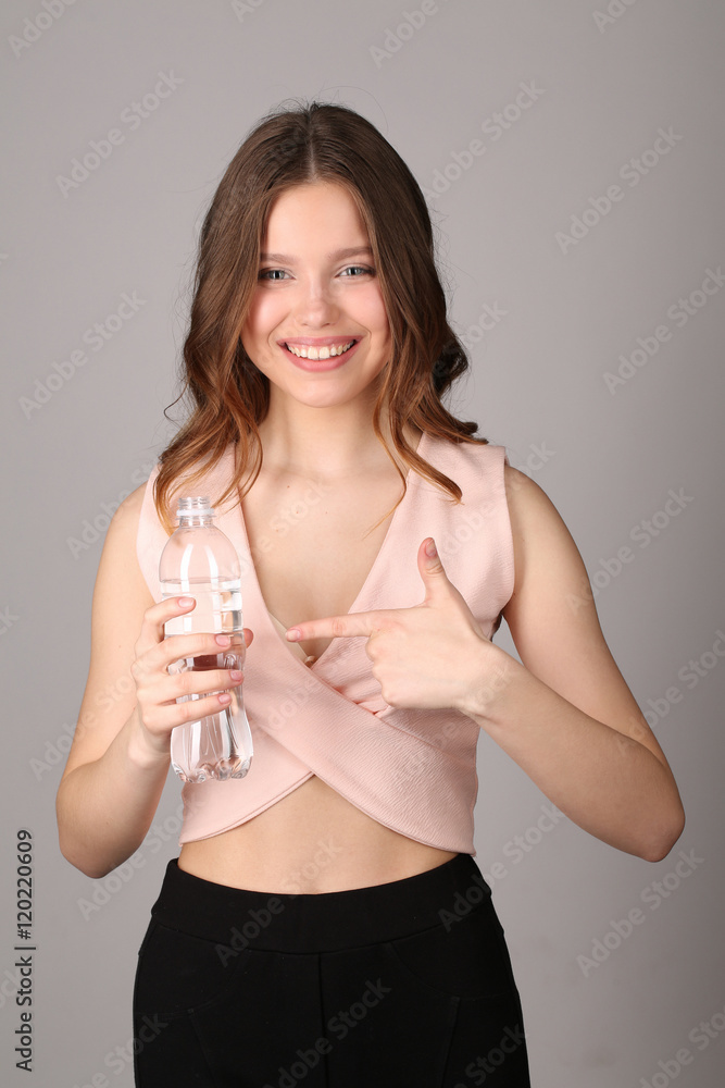 Lady points her finger at the bottle of water. Close up. Gray background Lady points her finger at the bottle of water. Close up. Gray background